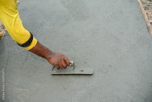 JASIN, MALAYSIA -FEBRUARY 5, 2016: Close-up of a hand using the trowel to finish and level wet concrete floor.