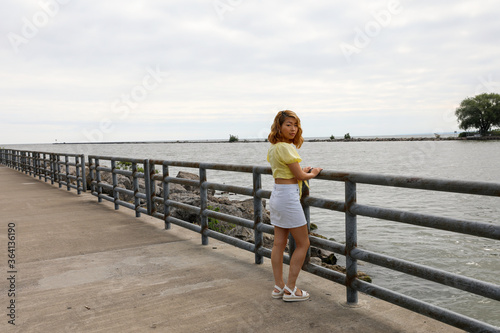 Young woman is enjoying the view of the water from the pier. Early summer morning on Lake Ontario.
