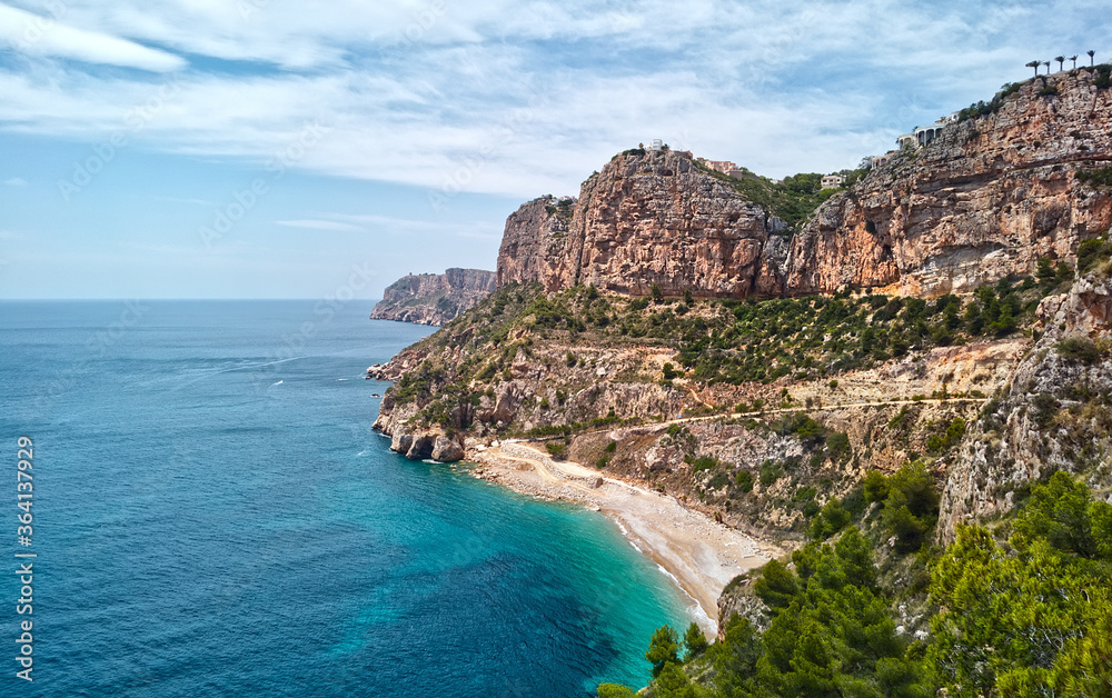 Aerial photo drone point of view picturesque Cala del Moraig in Benitachell coastal town. Bright turquoise waters bay of Mediterranean Sea white sandy beach, huge cliffs coastline. Costa Blanca. Spain - obrazy, fototapety, plakaty 