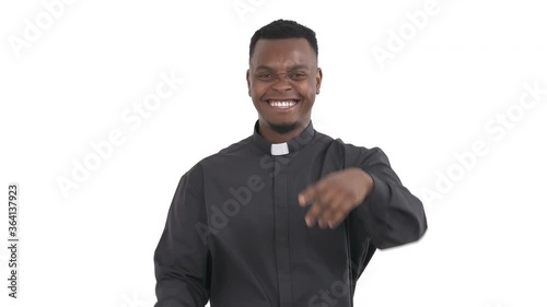 portrait of laughing black priest pointing on camera with forefinger expressing mockery emotion, making fun of someone isolated on white background
