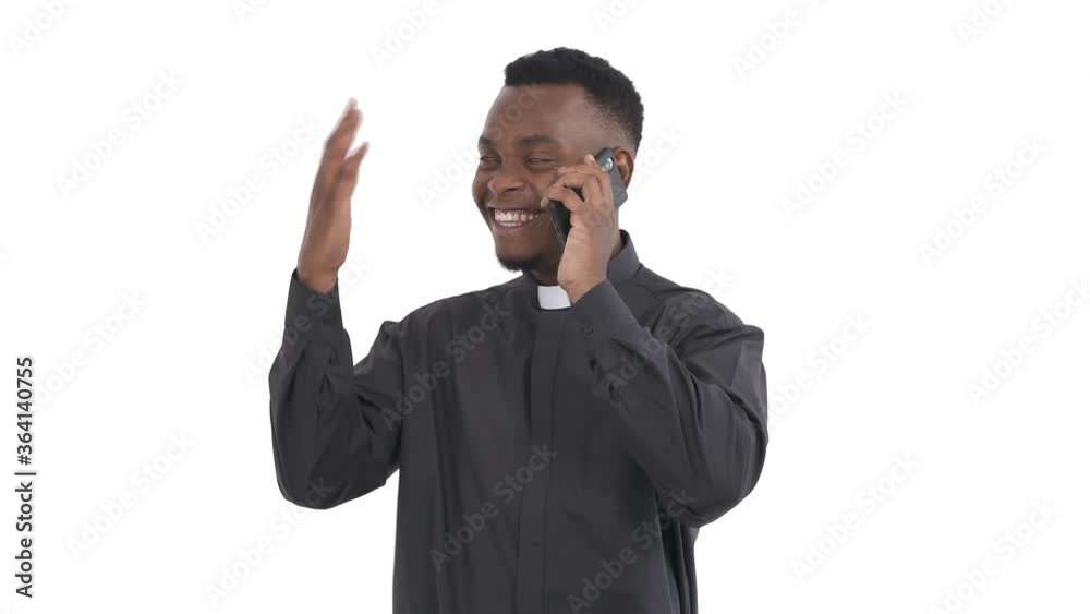 Portrait of young African priest calling on the phone, smiling, showing okay, happily and thankfully reacting to what he heard isolated on white background