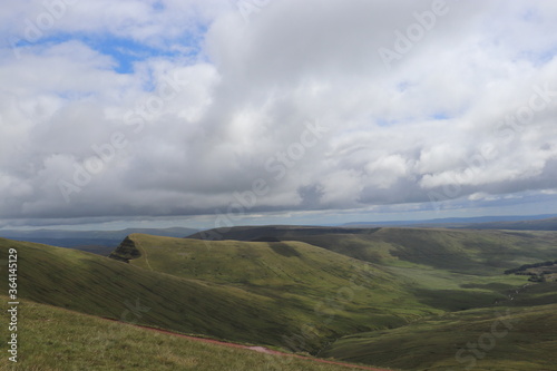 Green rolling hills with blue and white cloudy sky 