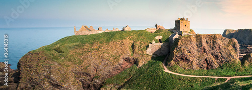 Medieval fortress Dunnottar Castle in sunset. The ruins of Dunottar Castle in sunset on the north east coast of Scotland. Old fairytale castle near sea. photo