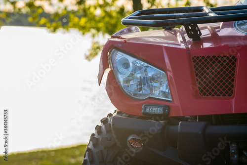 close-up front view of red atv quad bike, off road adventures, tours and travelling on all terrain vehicle in countryside