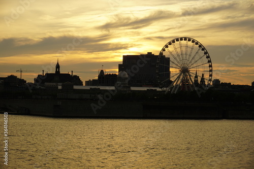 A skyline of Montreal Old Port at sunset. Foreground is Saint Laurent river © Rania