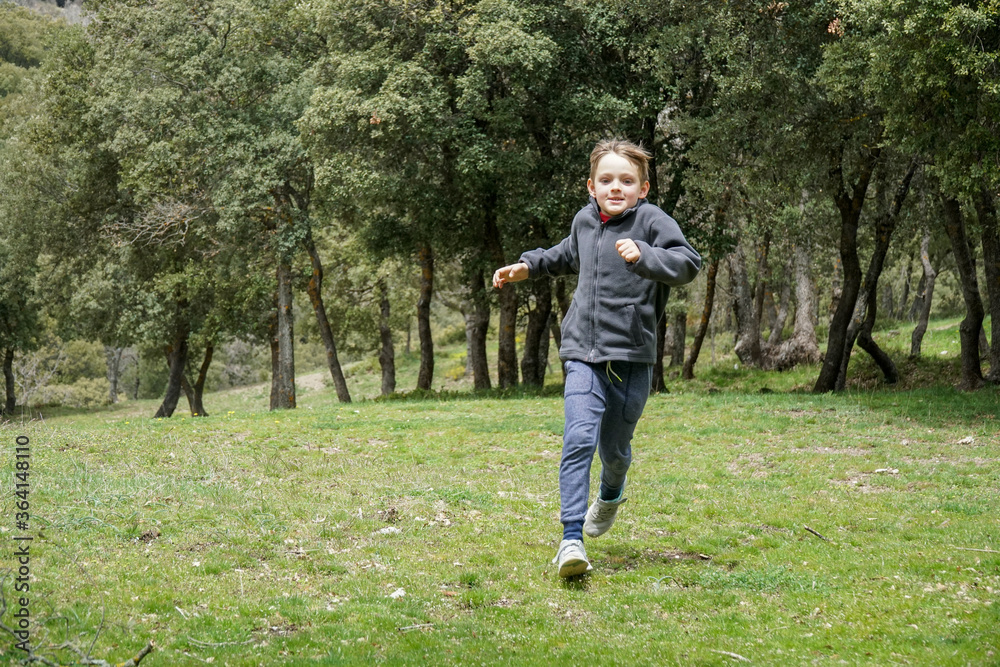 9 years old boy running on a meadow in a sunny day