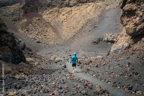 Hombre con jersey azul entra en el crater del volcan "El Cuervo" en Lanzarote. Islas Canarias. 2