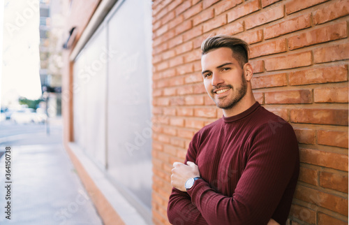 Young man against brick wall.