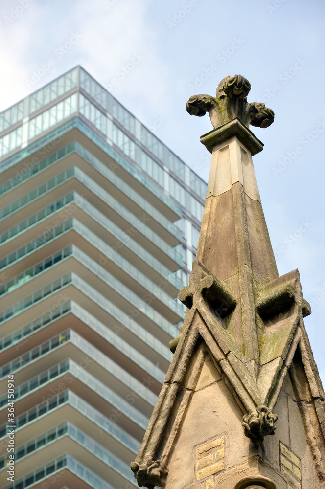 A gothic revival church steeple seen against a modern high-rise condo, a concept of old versus new.