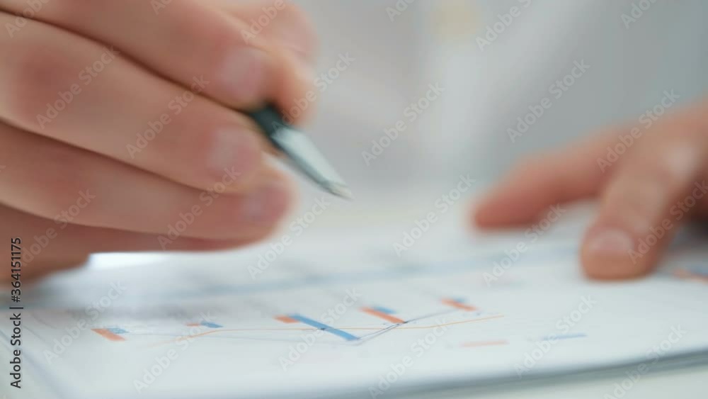 Close Up Of Businessman Hands Analyzing Business Report And Charts In Office. Business And Financial Success Concept. Close Up Of Businessman Hands Analyzing Business Report And Charts In Office. Business And Financial Success Concept.