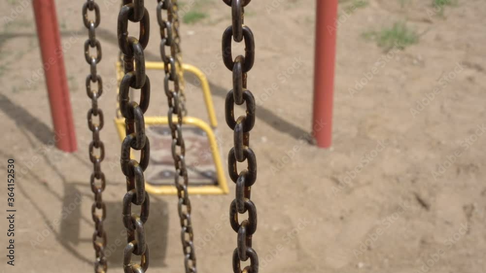outdated rusty chains of swings cast shadows on local playground yellow sand on sunny summer day slow motion close view outdated rusty chains of swings cast shadows on local playground yellow sand on sunny summer day slow motion close view