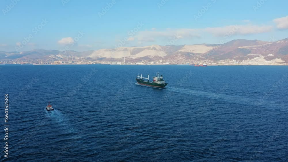 Aerial view following the ultra large cargo ship at sea leaves port at sunny day. Top down drone footage of tanker view from above. Concept of transport logistics, maritime. Aerial view following the ultra large cargo ship at sea leaves port at sunny day. Top down drone footage of tanker view from above. Concept of transport logistics, maritime.