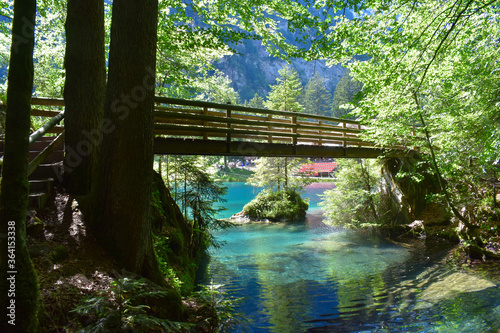 A bridge over a magnificent crystal-clear blue lake in the mountains. Swiss Alps. Summer mountain landscape. Blue water  forest.