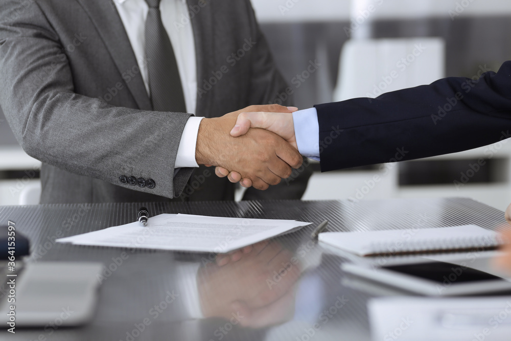 Unknown business people are shaking hands after contract signing in modern office, close-up. Handshake as successful negotiation ending