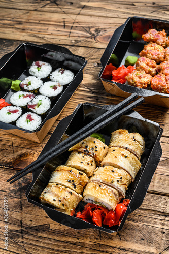 The sushi rolls in the delivery package, ordered in sushi take-out restaurant.  Wooden background. Top view