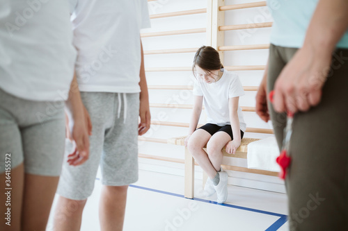 Sad little girl sitting alone on a bench during physical education classes at school photo