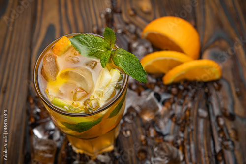 ice tea with apple and orange on a brown wooden table. Decorated with mint.