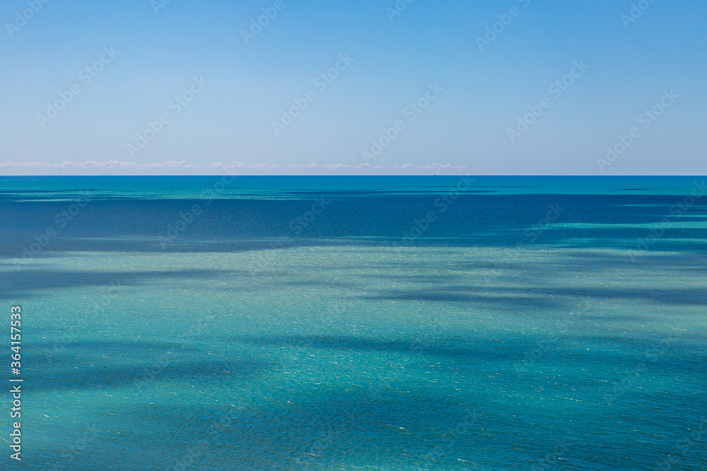 Light and shade in the ocean, with a clear sky overhead