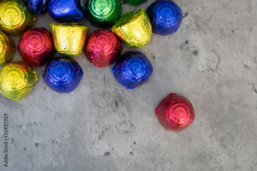 Chocolate bonbons in multicolored foil wraps scattered on the table. Flat lay with colorful sweets and empty space for text