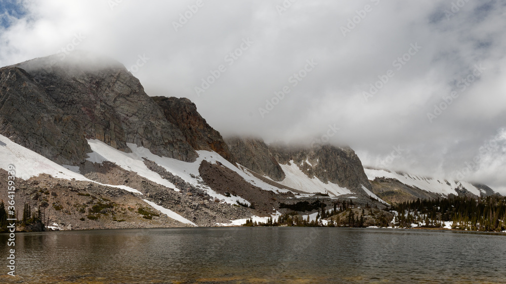 Lake Marie in Wyoming's Snowy Range remains calm under storm clouds.