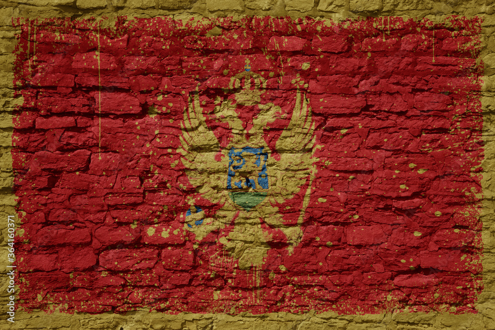 Fototapeta premium painted big national flag of montenegro on a massive old brick wall