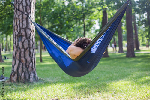 Young guy has a rest in summer in a hammock