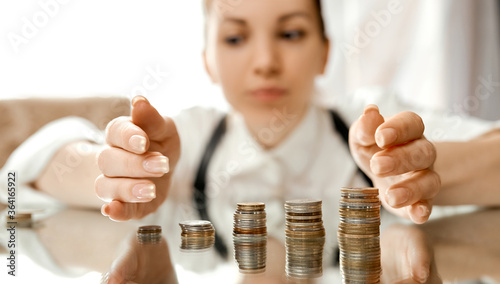 A woman collects stacks of coins to the center on a mirrored table  photo