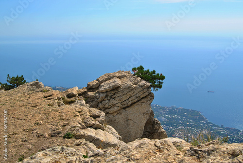 A rock of unusual shape high above the city and the sea coast on a sunny day.