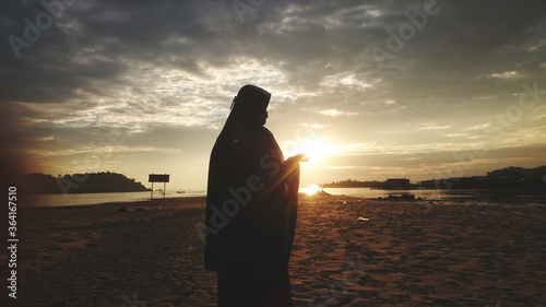 A muslim woman on the beach before sunset