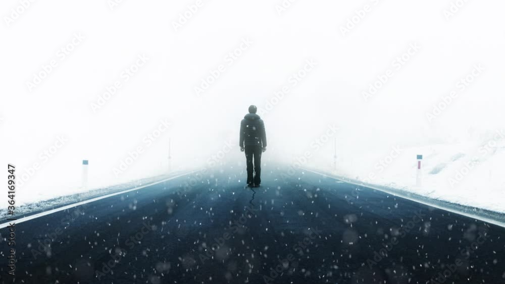 Man stands alone on the asphalt foggy road during snowfall. Winter conditions with people. Man stands alone on the asphalt foggy road during snowfall. Winter conditions with people.