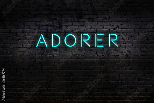 Night view of neon sign on brick wall with inscription adorer