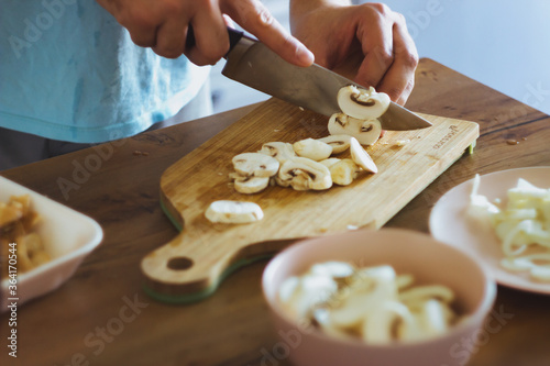 a young chef cuts mushrooms and cooks chicken. Cooking julienne, prepare meat at home