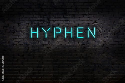 Photos Neon sign. Word hyphen against brick wall. Night view