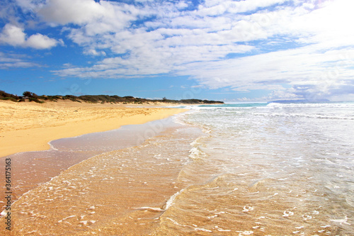 Polihale State Park, Kauai. The view on the empty sandy beach with clear waters of Pacific ocean. Cloudy blue sky. photo