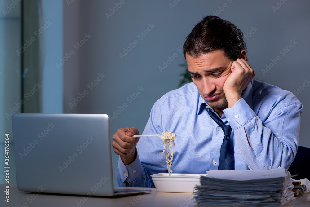 Hungry employee working late in the office Hungry employee working late in the office