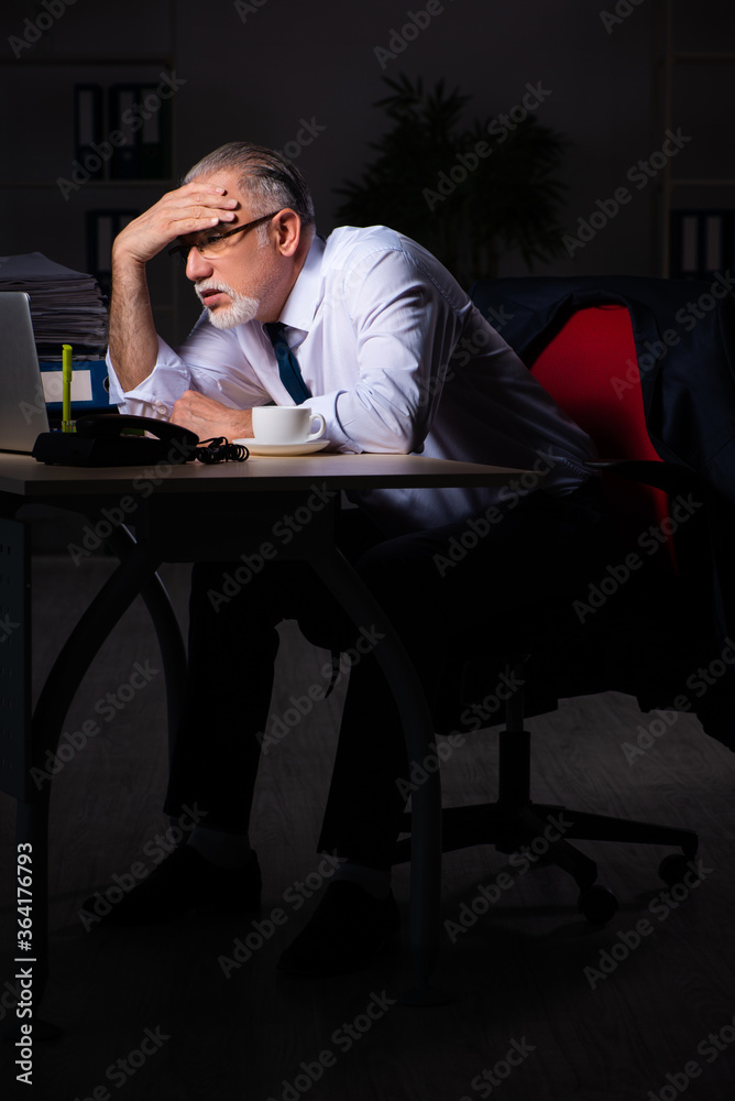 Old male employee working late at workplace Old male employee working late at workplace