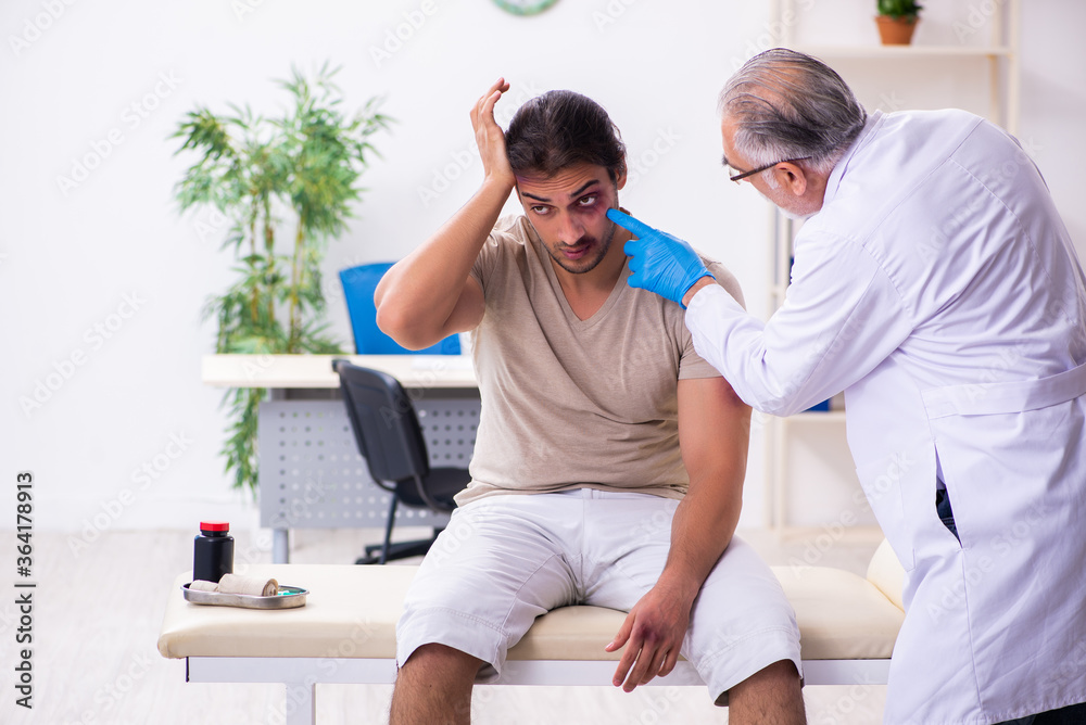 Fototapeta premium Young face injured man visiting experienced male doctor traumato