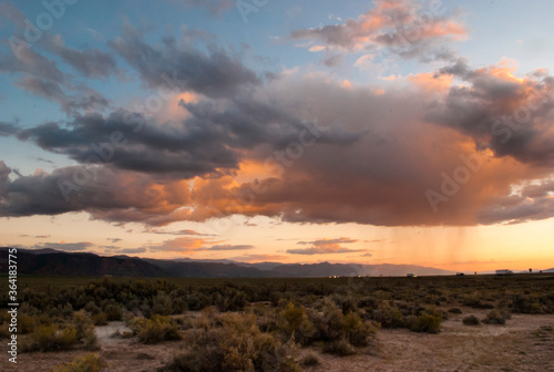 Sunset, thunderclouds, orange sky and patchy rain in the Mojave desert with I-15 freeway in the background 