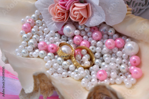 Wedding rings in a shell with pink pearls.