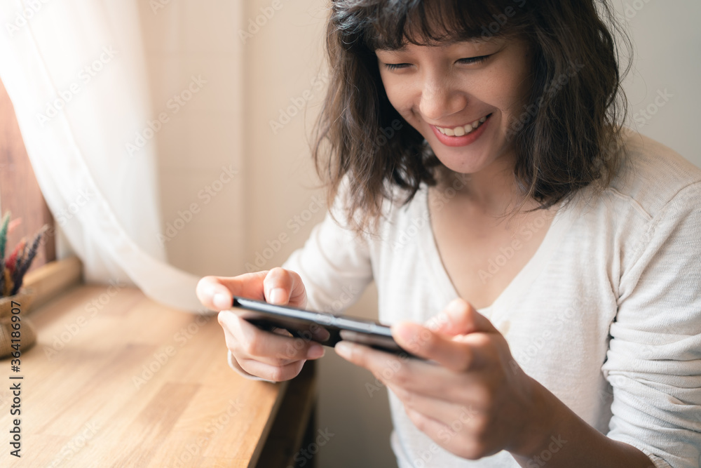 Close up of young Asian woman using smartphone watching video clip and playing online game. A happy female with smiley face. technology business and social distancing concept Close up of young Asian woman using smartphone watching video clip and playing online game. A happy female with smiley face. technology business and social distancing concept