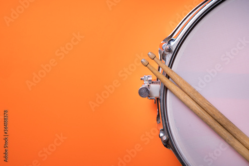 Canvas-taulu Drum stick and drum on orange table background, top view, music concept