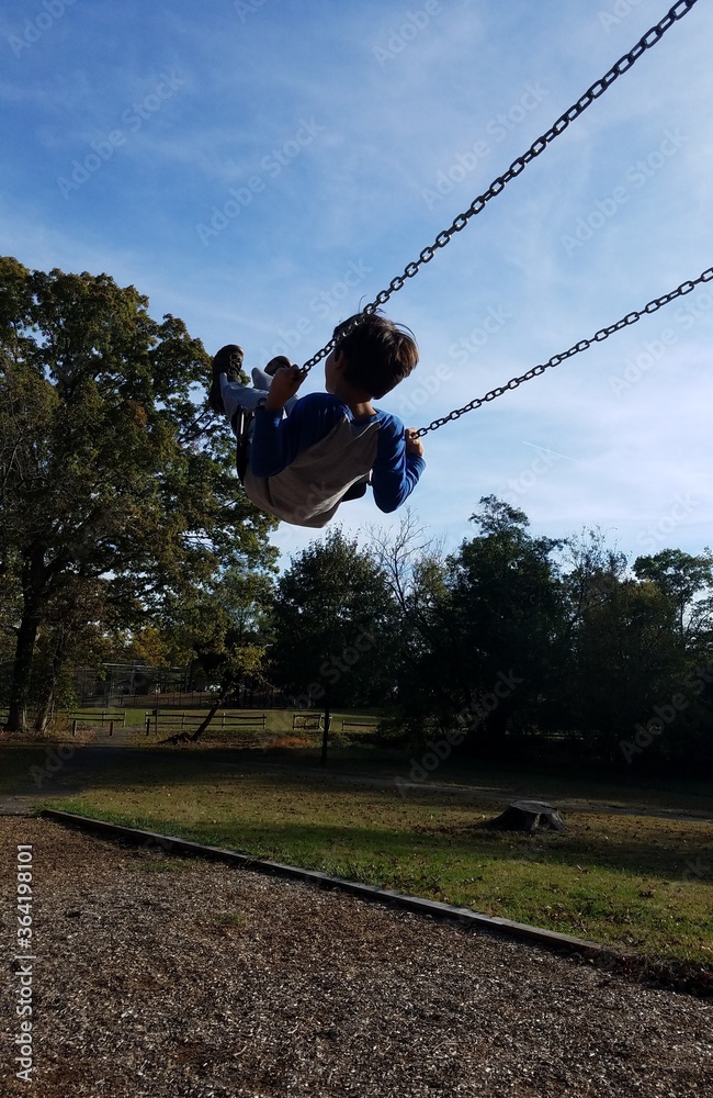 boy child swinging on swing at playground