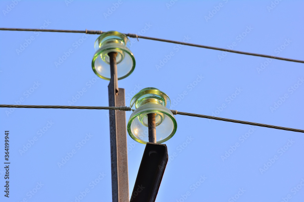 Fototapeta premium A garland of insulators on electric wires of a metal high-voltage support.