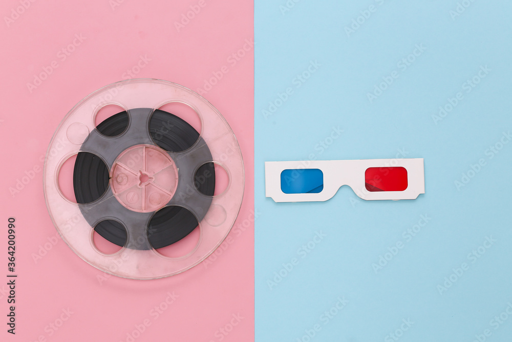 Film reel and anaglyph 3D glasses on pink blue background. Entertainment industry. Cinema. Top view