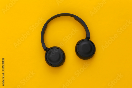 Black stereo headphones on yellow background. Top view