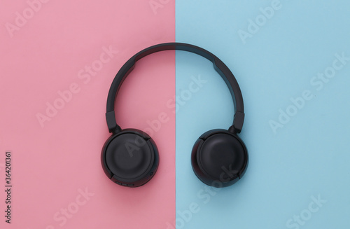 Black stereo headphones on pink blue pastel background. Top view