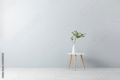 wooden round coffee table and greenplant in front of empty interior wall. photo