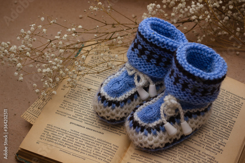 Handmade crocheted booties on an old vintage book with dried flowers