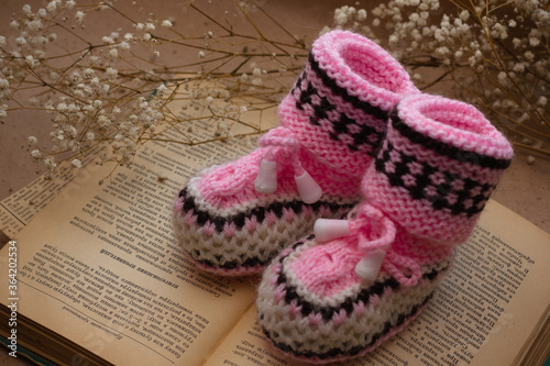 Handmade crocheted booties on an old vintage book with dried flowers
