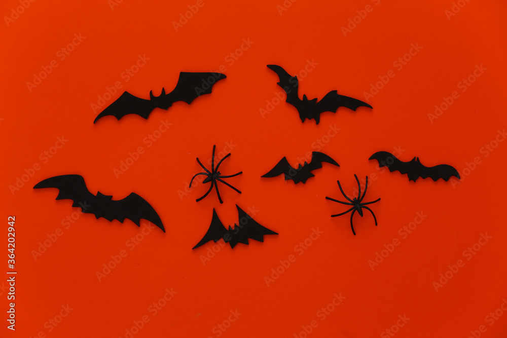 Halloween background, decorations and scary concept. Spiders and black bats fly over orange background. Top view Halloween background, decorations and scary concept. Spiders and black bats fly over orange background. Top view